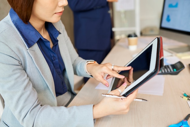 Nahaufnahme einer Unternehmerin, die eine Anwendung auf einem Tablet-Computer verwendet oder einen Bericht liest