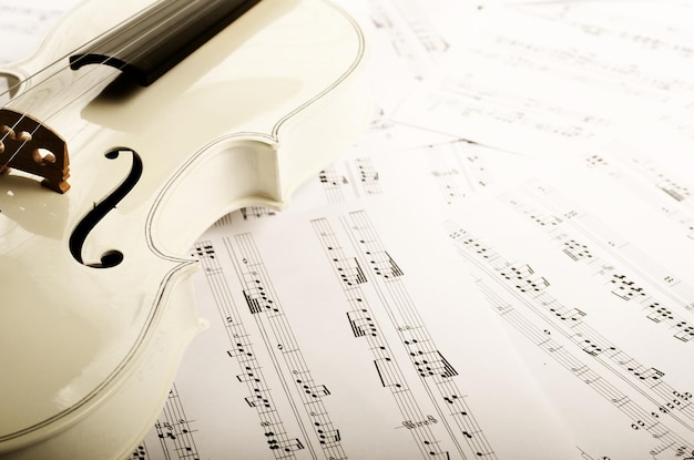 Foto nahaufnahme einer violine und musiknoten auf weißem holztisch