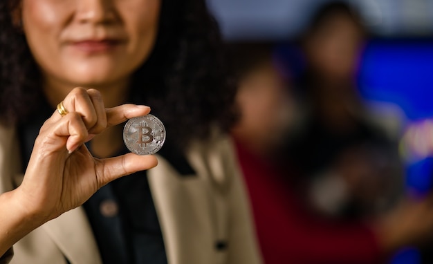 Nahaufnahme einer virtuellen Token-Münze der Silber-Bitcoin-Kryptowährung in professioneller erfolgreicher weiblicher Geschäftsfrau-Trader-Investorhand mit Kopienraum in unscharfem Hintergrund.