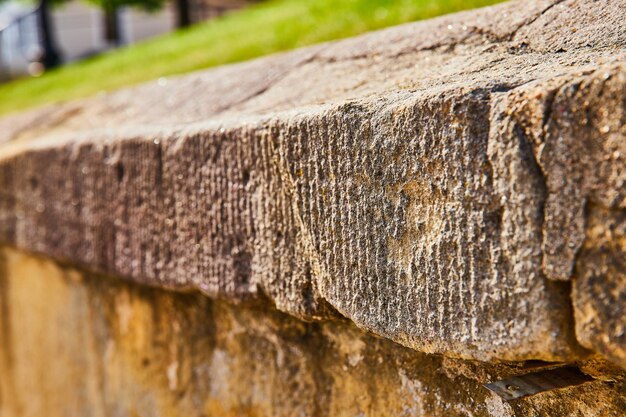 Nahaufnahme einer vom Wetter abgenutzten Betonmauer mit Gras oben