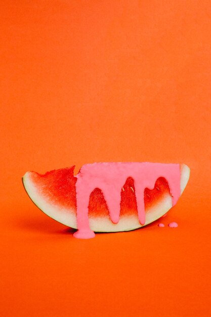 Nahaufnahme einer Wassermelone mit Sahne vor orangefarbenem Hintergrund