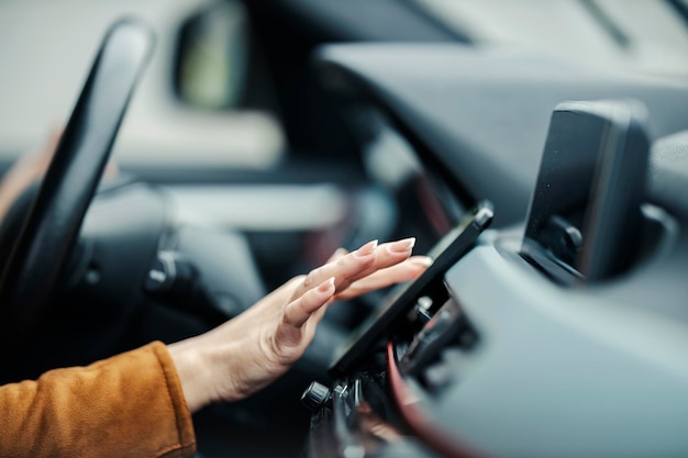 Nahaufnahme einer weiblichen Hand, die das Telefon in einem Auto richtig benutzt