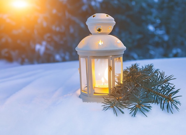 Nahaufnahme einer Weihnachtslaterne im Schnee mit winterlichem Waldhintergrund