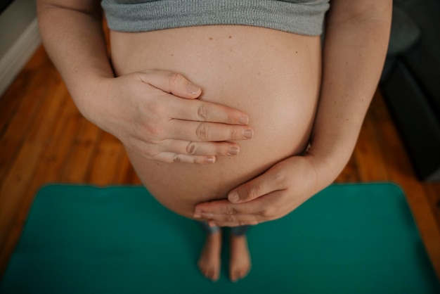 Nahaufnahme einer werdenden Mutter, die steht und sanft ihren Bauch berührt