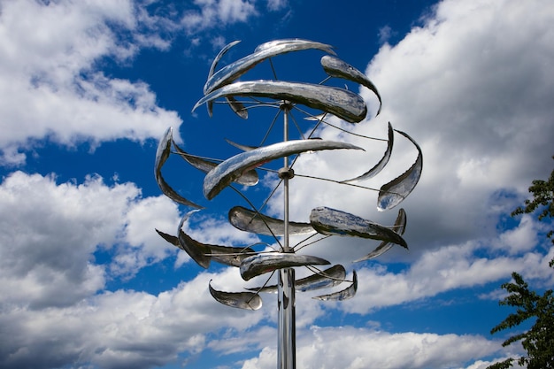 Nahaufnahme einer windkinetischen Skulptur vor einem wolkigen Himmelshintergrund