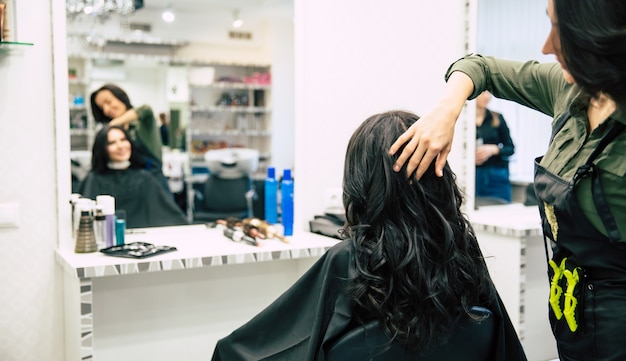 Nahaufnahme einer wunderschönen Frau mit schönem, welligem Haar, die sich in einem Schönheitssalon die Haare machen lässt.