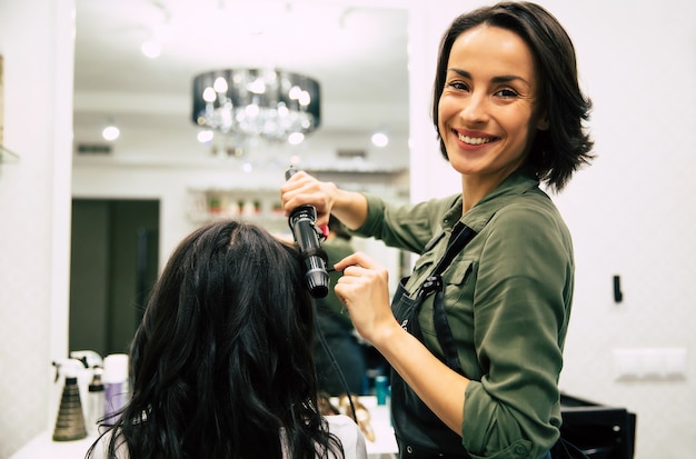 Nahaufnahme einer wunderschönen Frau mit schönem, welligem Haar, die sich in einem Schönheitssalon die Haare machen lässt.