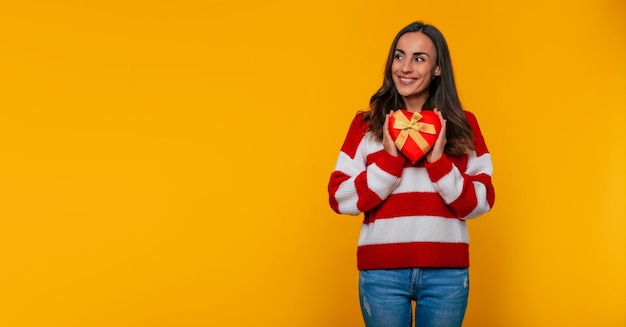 Nahaufnahme einer wunderschönen, glücklichen brünetten Frau mit Geschenkbox in Form eines Herzens in den Händen ihrer Geliebten