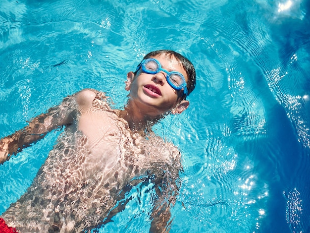 Nahaufnahme eines 8-jährigen Jungen, der auf einem Pool schwimmt, Sommerspaßkonzept