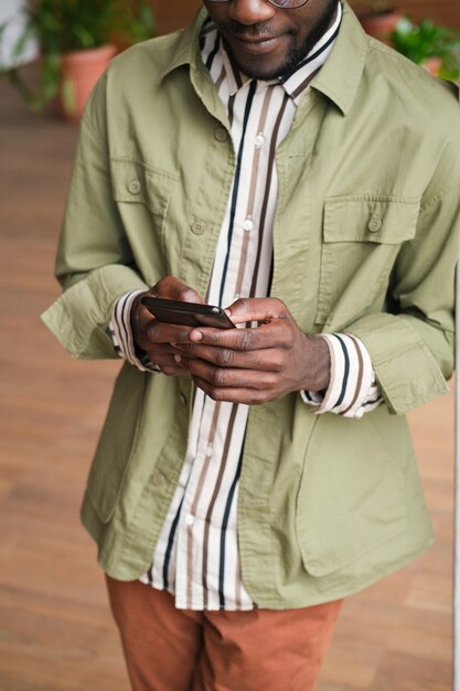 Nahaufnahme eines afrikanischen jungen Mannes, der online auf dem Handy kommuniziert