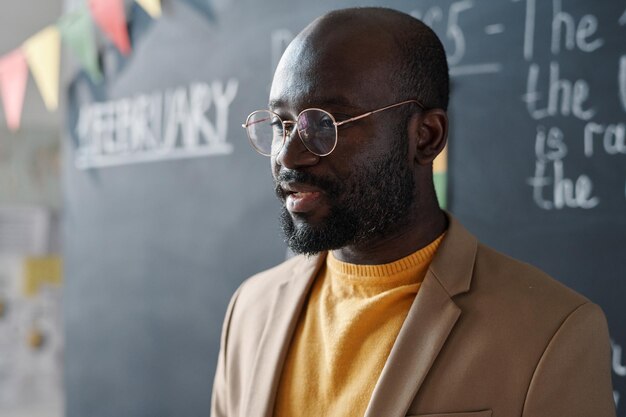 Foto nahaufnahme eines afroamerikanischen lehrers mit brille, der bei einem vortrag vor der tafel spricht