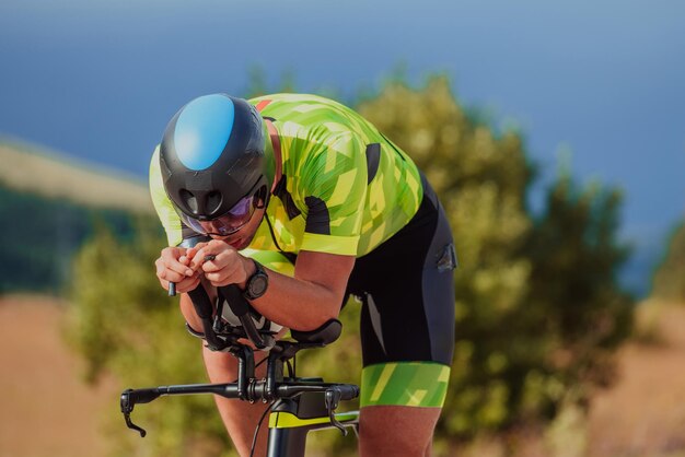 Nahaufnahme eines aktiven Triathleten in Sportbekleidung und mit Schutzhelm beim Fahrradfahren. Selektiver Fokus.