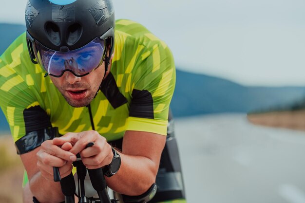 Nahaufnahme eines aktiven Triathleten in Sportbekleidung und mit Schutzhelm beim Fahrradfahren. Selektiver Fokus.