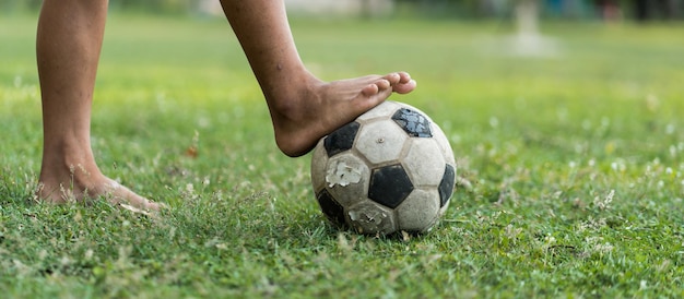 Foto nahaufnahme eines alten fußballjungen, der keine schuhe trägt und bereit ist, den ball auf dem alten fußballfeld zu treten