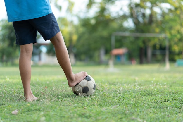 Nahaufnahme eines alten Fußballjungen, der keine Schuhe trägt und bereit ist, den Ball auf dem alten Fußballfeld zu treten