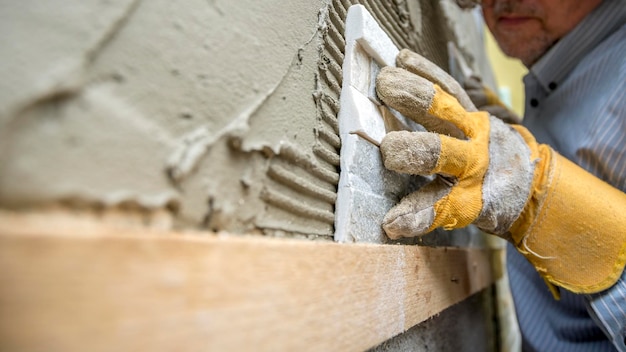 Nahaufnahme eines Arbeiters, der eine dekorative Fliese sorgfältig in einem Kleber positioniert