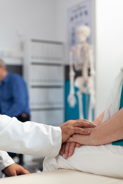 Foto nahaufnahme eines arztes, der eine frau im ruhestand mit körperlichen schmerzen unterstützt und die hände des patienten hält, um genesung und abhilfe zu gewährleisten. sanitäter, der eine ältere person mit arthritis bei der physiotherapie tröstet