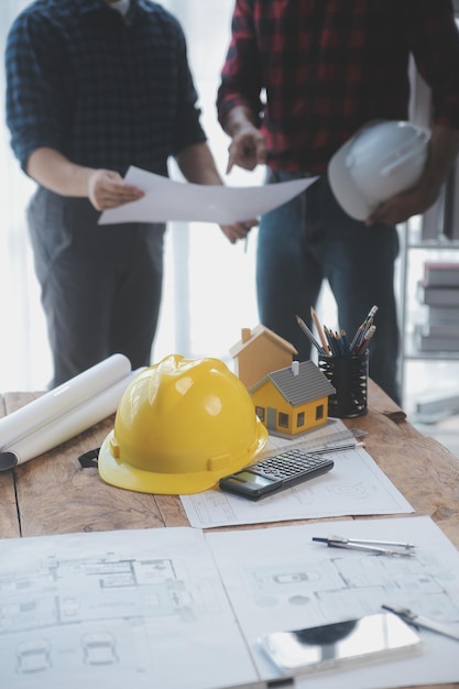 Nahaufnahme eines asiatischen Bauingenieurs, der auf der Baustelle am Schreibtisch im Büro an einem Architekturprojekt arbeitet