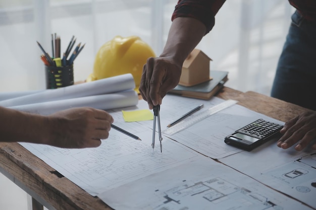 Nahaufnahme eines asiatischen Bauingenieurs, der auf der Baustelle am Schreibtisch im Büro an einem Architekturprojekt arbeitet