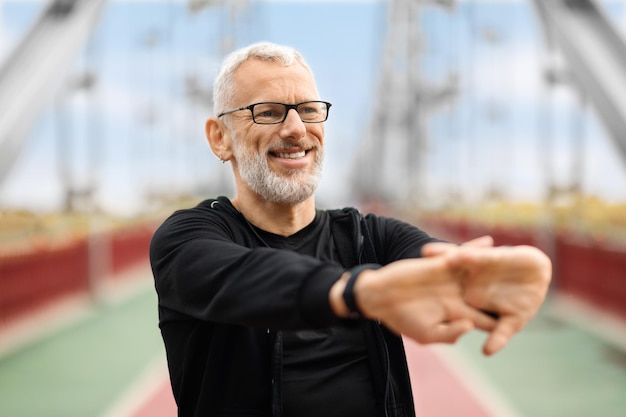 Foto nahaufnahme eines athletischen älteren sportlers, der seine arme ausstreckt und im freien trainiert