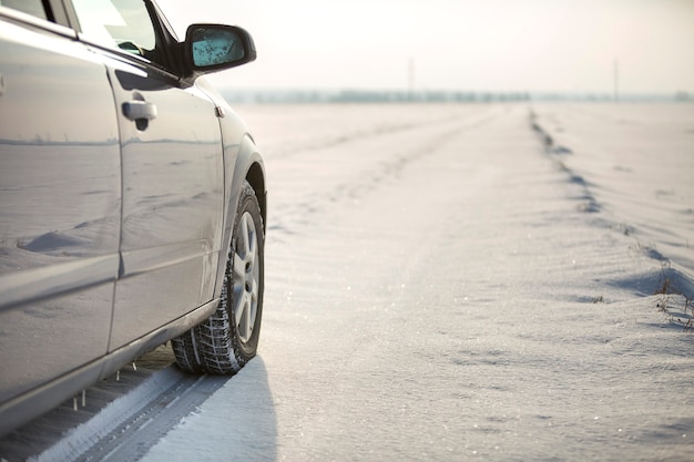 Nahaufnahme eines Autoreifens auf verschneiter Straße am Wintertag geparkt. Transport- und Sicherheitskonzept.