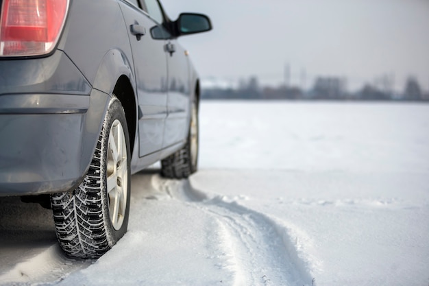 Nahaufnahme eines Autoreifens auf verschneiter Straße am Wintertag geparkt. Transport- und Sicherheitskonzept.