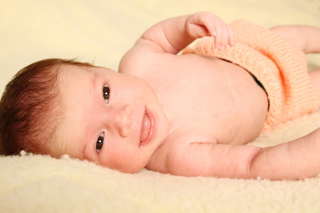 Nahaufnahme eines Babys, das in gestrickten Windeln auf einer Decke liegt