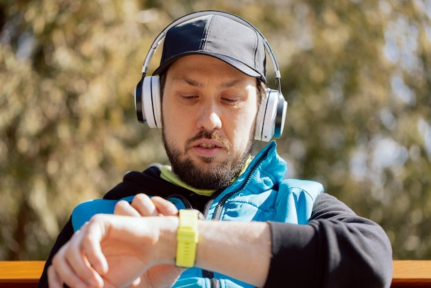 Nahaufnahme eines bärtigen Athleten, der nach dem Training die Herzfrequenz der Fitnessergebnisse überprüft