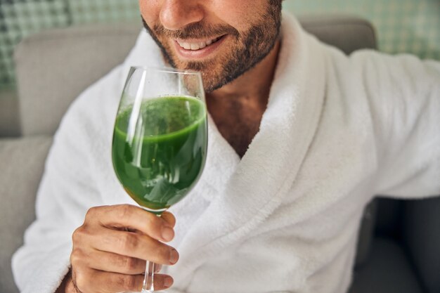 Nahaufnahme eines bärtigen Herrn, der ein Glas frisches gesundes Getränk hält und lächelt