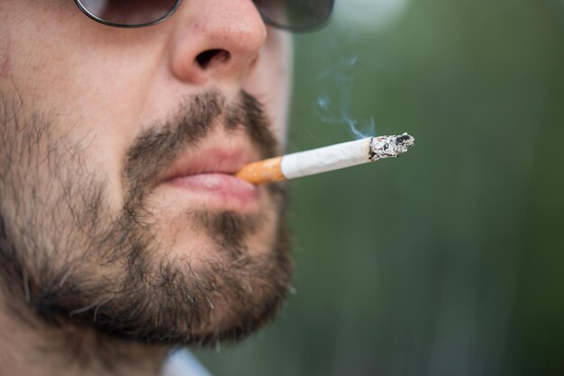 Foto nahaufnahme eines bärtigen mannes in sonnenbrille, der eine zigarette raucht