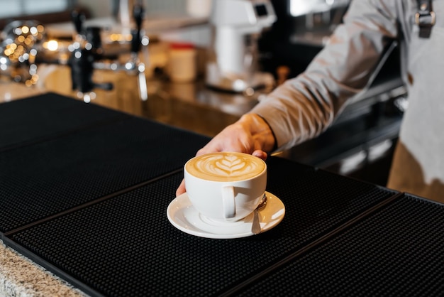 Nahaufnahme eines Baristas, der während einer Pandemie köstlichen Kaffee an der Bar serviert Zubereitung und Servieren in einem Café