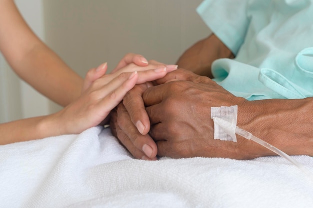 Nahaufnahme eines Besuchers, der die Hand älterer Patienten im Krankenhaus und im medizinischen Konzept hält
