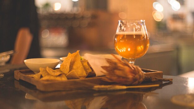 Foto nahaufnahme eines bierglases mit blumen und nachos, die auf dem tisch serviert werden