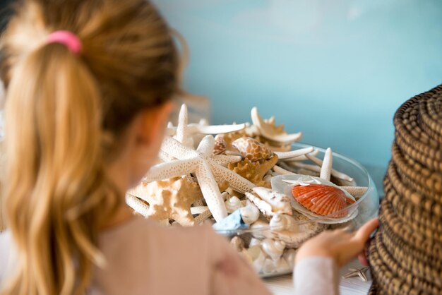 Foto nahaufnahme eines blonden mädchens mit muscheln zu hause