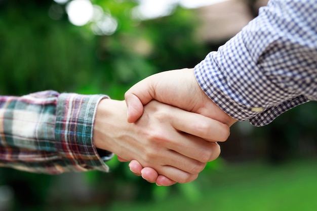 Nahaufnahme eines Business-Handshake zwischen zwei Kollegen Kariertes Hemd