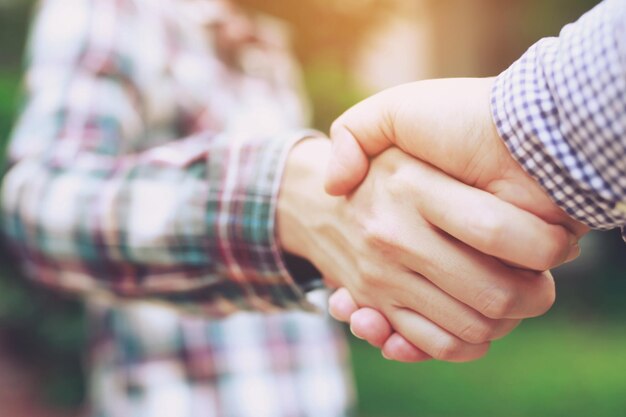 Nahaufnahme eines Business-Handshake zwischen zwei Kollegen Kariertes Hemd