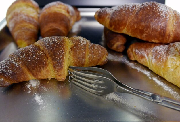 Foto nahaufnahme eines croissants mit gabel auf dem teller beim frühstück