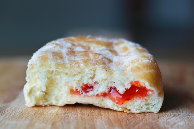 Foto nahaufnahme eines donuts mit erdbeermarmelade auf dem tisch