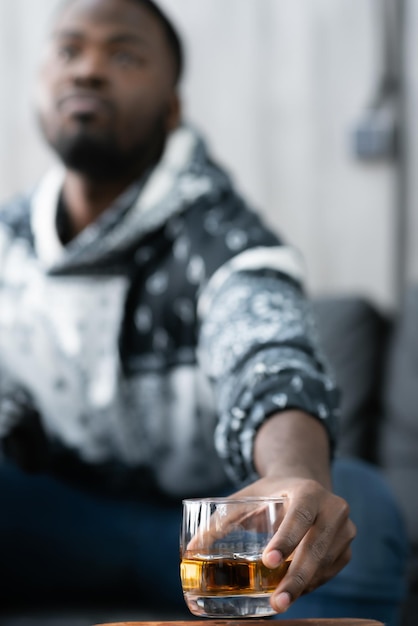 Nahaufnahme eines dunkelhäutigen Mannes, der ein Glas Whisky hält