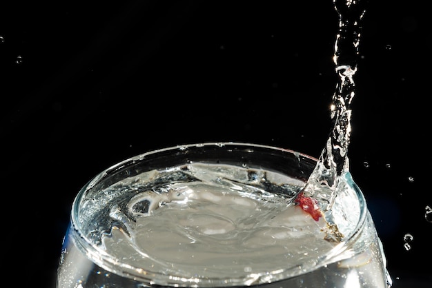 Foto nahaufnahme eines durchsichtigen glasbechers mit wasser im inneren und tropfen, die einen spritz machen