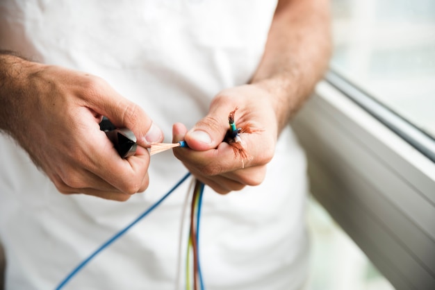 Foto nahaufnahme eines elektrikers, der plastikummantelung des kabels entfernt