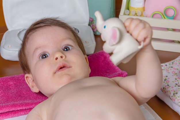 Nahaufnahme eines entzückenden Babys, das nach dem Windelwechsel mit einem Spielzeuggummi für Kinder spielt