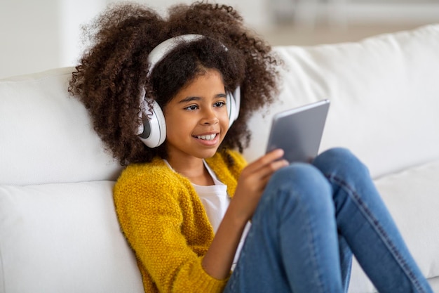 Nahaufnahme eines entzückenden schwarzen Mädchens mit digitalem Pad und Headset