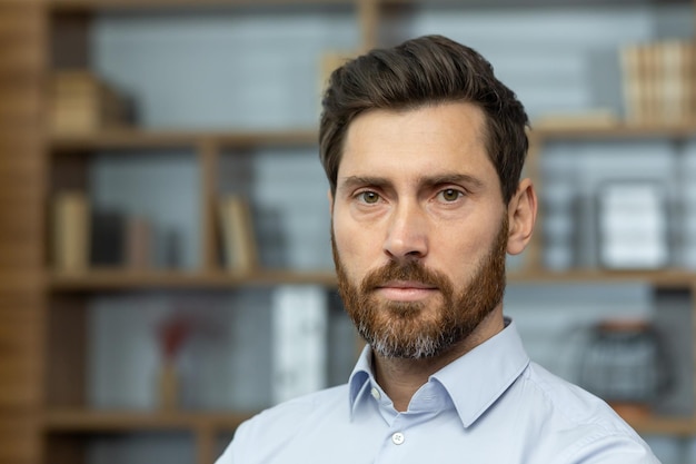 Nahaufnahme eines ernsthaften Chefs im Hemd im Heimbüro, reifer Mann mit Bart, der in die Kamera schaut