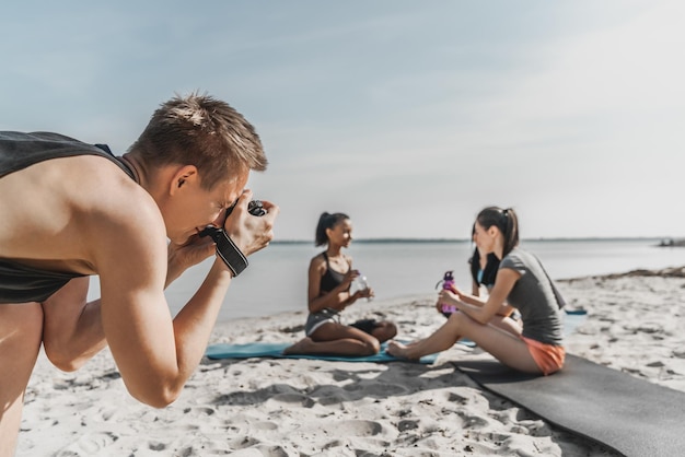 Nahaufnahme eines Fotografen, der eine Gruppe von Frauen fotografiert, die sich nach dem Fitness ausruhen