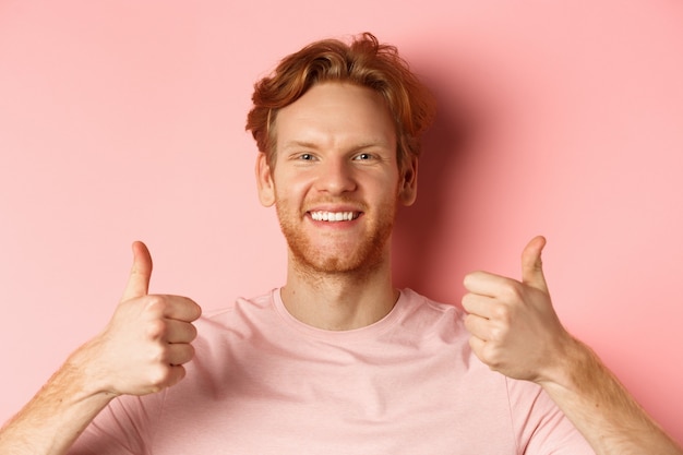 Foto nahaufnahme eines fröhlichen mannes mit roten haaren und bart, der daumen nach oben zeigt und lächelnd sagt, ja, genehmige...