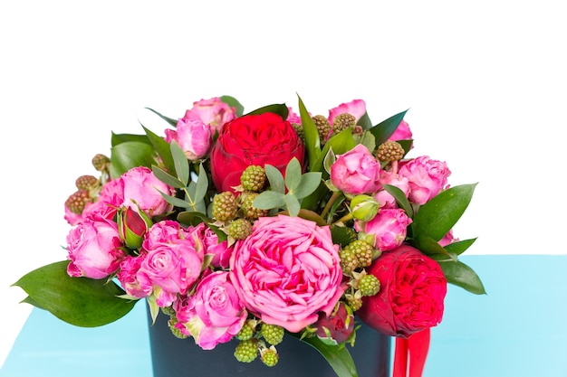 Nahaufnahme eines galanten Straußes aus rosa und roten Rosen und rotem Band in einer runden schwarzen Box. Valentinstag und Jubiläumskonzept