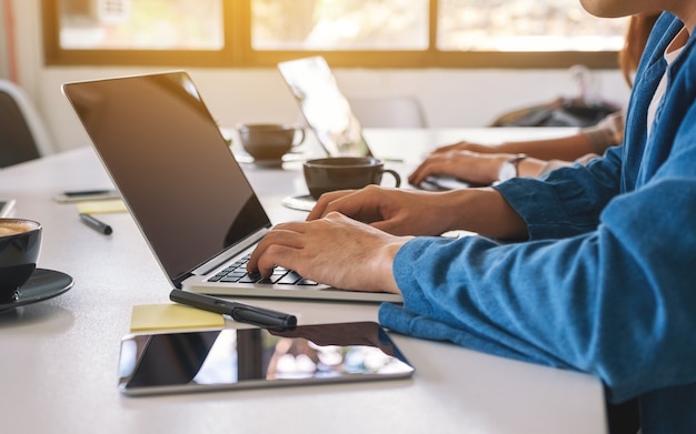 Nahaufnahme eines Geschäftsmannes, der einen Laptop mit Tablet-PC auf dem Tisch im Büro verwendet und arbeitet