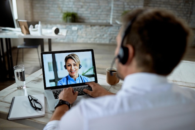 Nahaufnahme eines Geschäftsmannes, der während der Arbeit im Büro einen Videoanruf mit einem Arzt führt