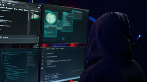 Nahaufnahme eines Hackers, der Code in einer Wohnung auf PC-Monitoren ausführt